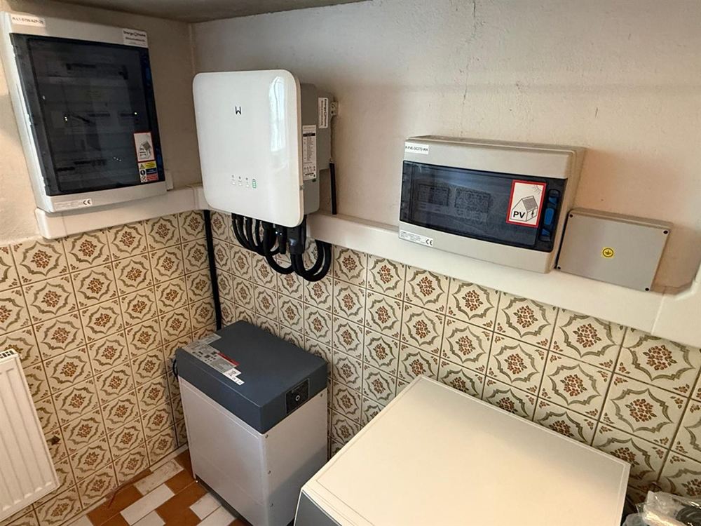 Střídač, baterie a dva rozvaděče na stěně s obkladem