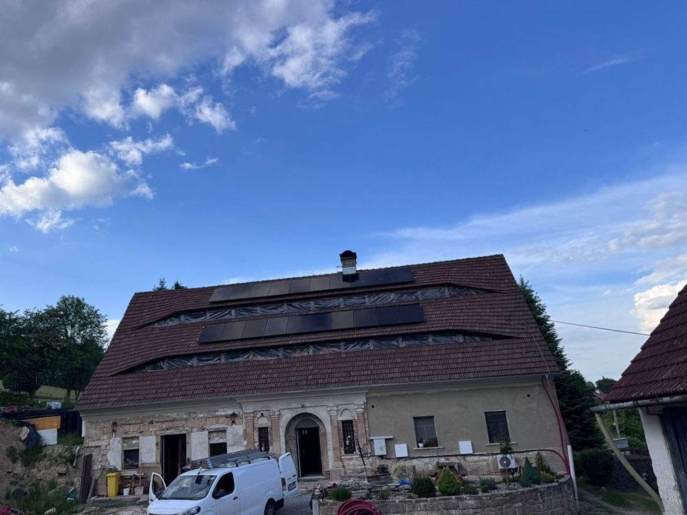 Historický statek s dvěma řadami černých panelů na taškové střeše