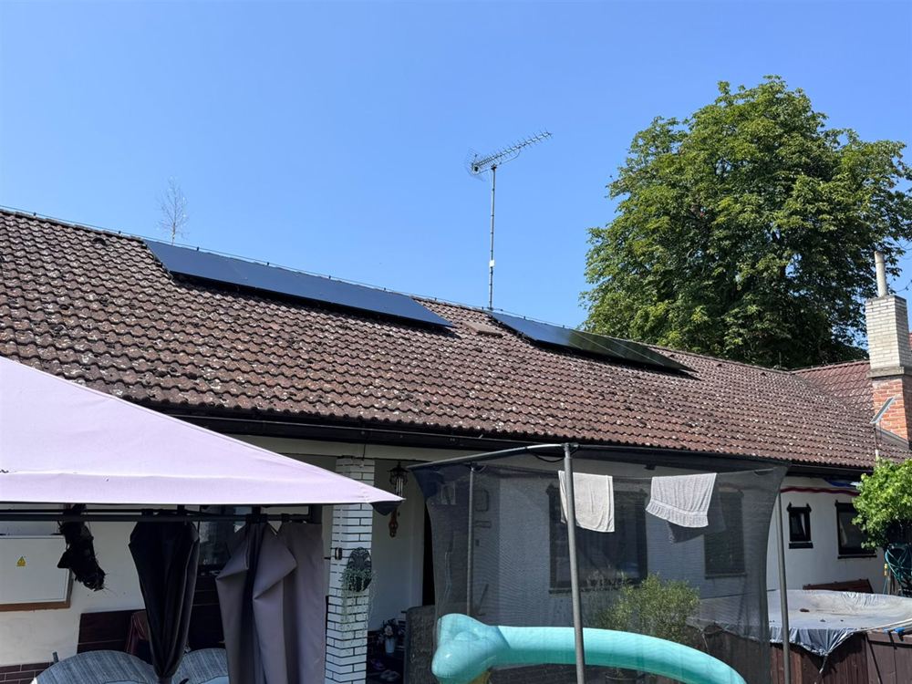 Dvě pole černých panelů na taškové střeše přízemního domu