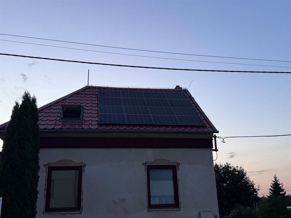 Rodinný dům s panely na červené střeše za soumraku