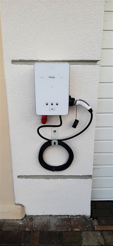 Nabíjecí stanice wallbox s kabelem na fasádě domu