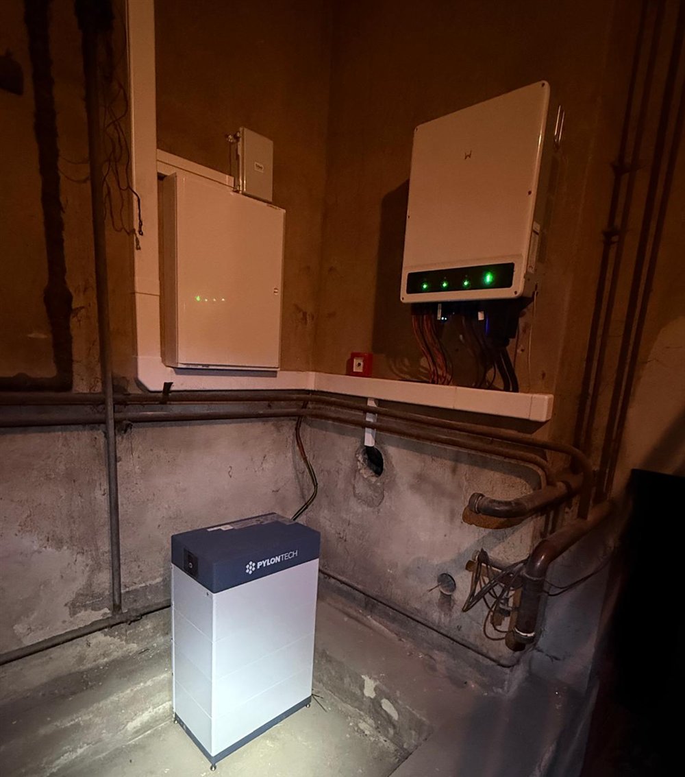 Střídač, rozvaděč a bateriový modul Pylontech v tmavém sklepě po revizi
