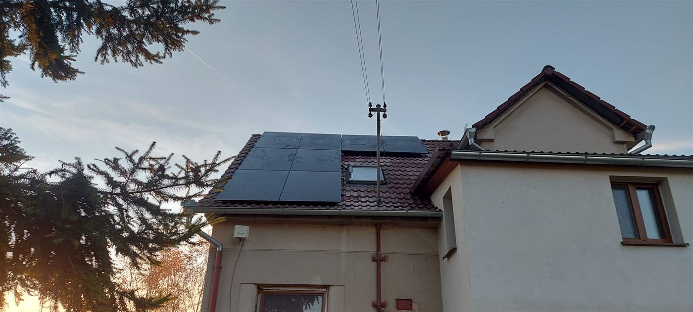 Černé panely na taškové střeše domu při západu slunce