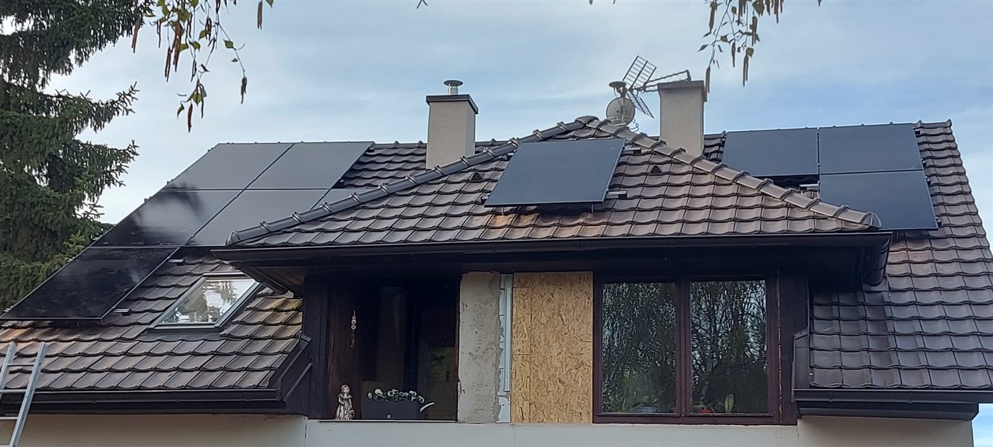 Dům s černými panely na třech částech taškové střechy