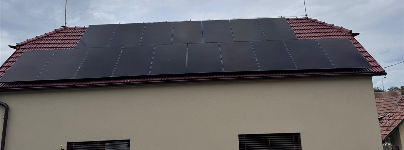 Dvě řady černých panelů na červené taškové střeše domu