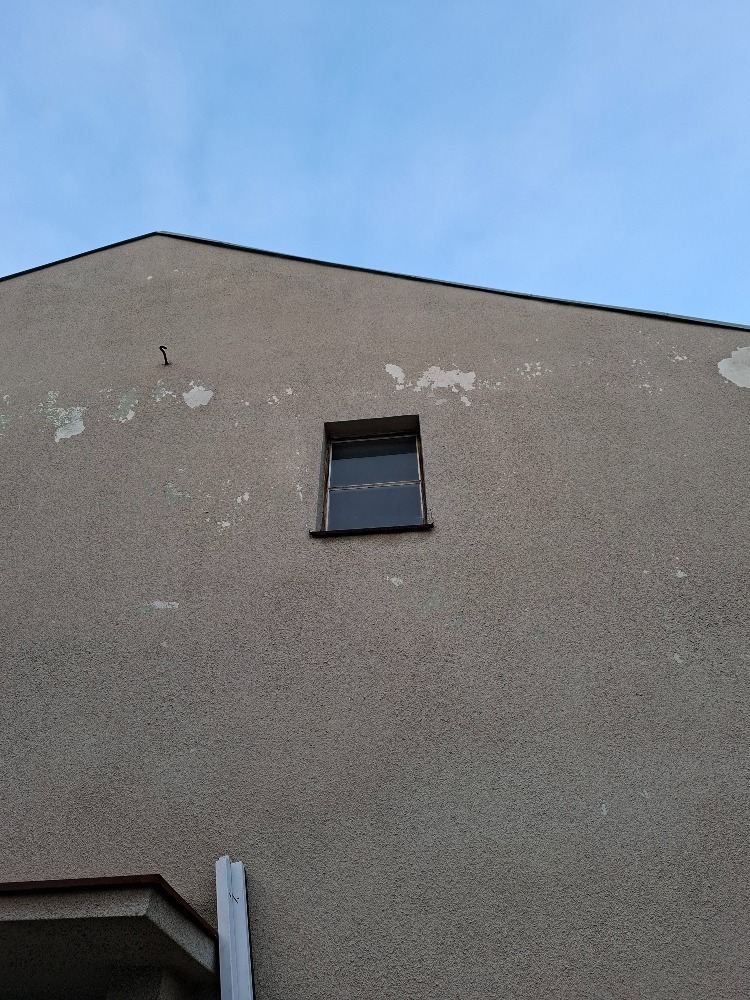 Štít domu se starým malým oknem před výměnou